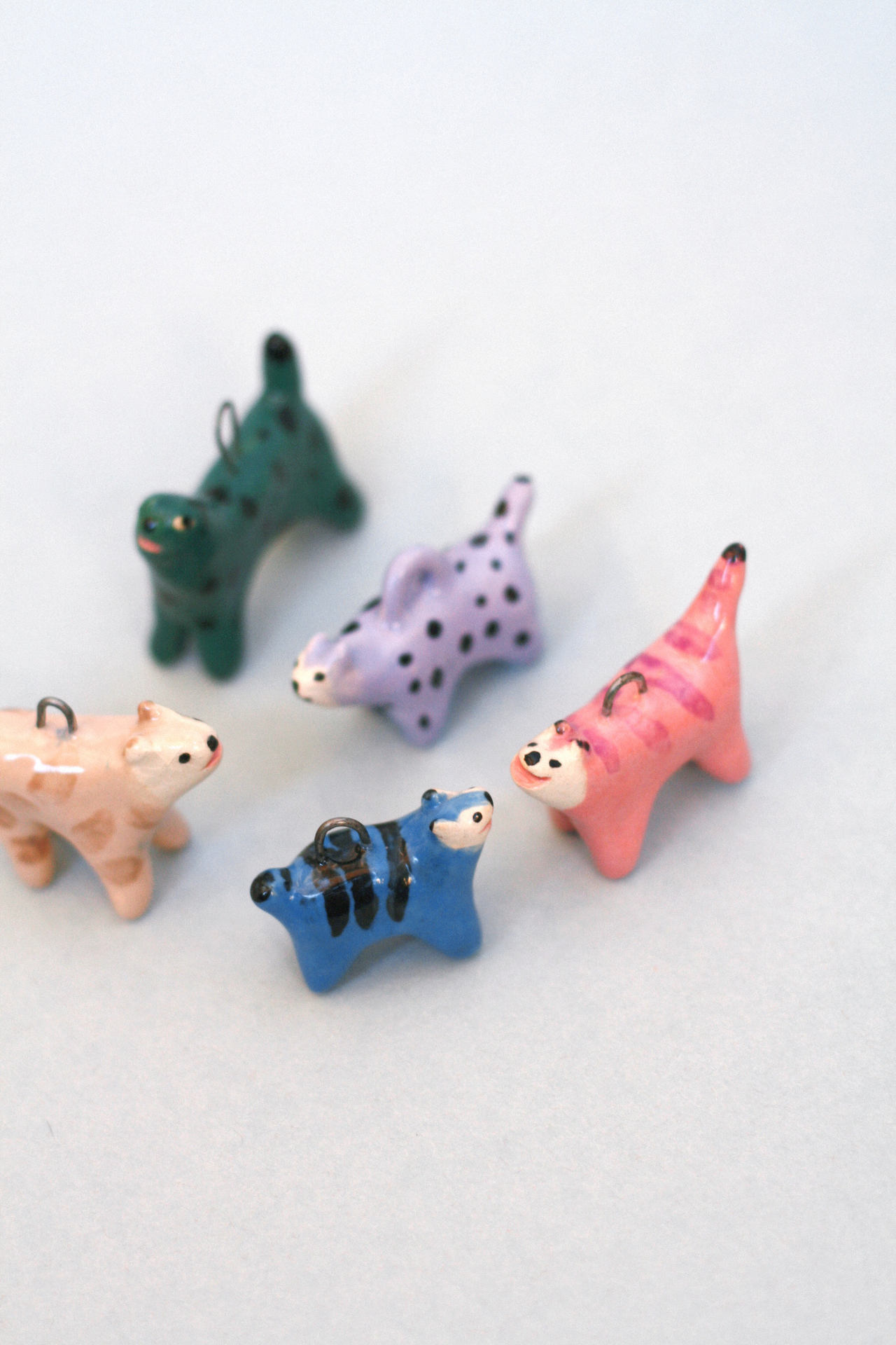 Handmade ceramic cat charms in colorful designs by Anja Bartelt